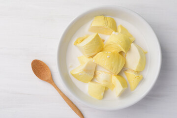 Thai dessert, sliced durian fruit with coconut milk in a bowl on white table background