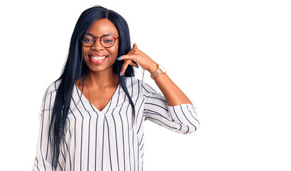 Young african american woman wearing casual clothes and glasses smiling doing phone gesture with hand and fingers like talking on the telephone. communicating concepts.