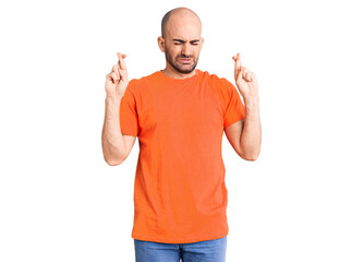 Young handsome man wering casual t shirt gesturing finger crossed smiling with hope and eyes closed. luck and superstitious concept.