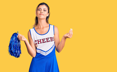 Young beautiful woman wearing cheerleader uniform doing money gesture with hands, asking for salary...