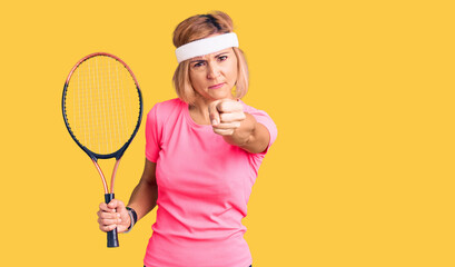 Young blonde woman playing tennis holding racket annoyed and frustrated shouting with anger, yelling crazy with anger and hand raised