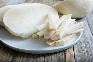 A view of a jicama cut into a variety of slice portions, on a plate.
