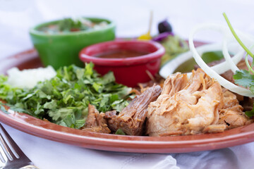 A view of a carnitas plate, in a restaurant or kitchen setting.
