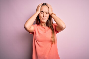 Young beautiful woman wearing casual t-shirt standing over isolated pink background suffering from headache desperate and stressed because pain and migraine. Hands on head.