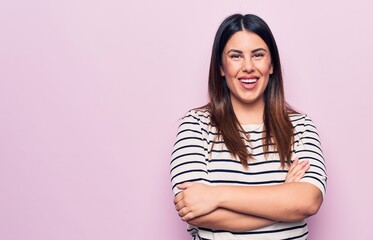 Obraz na płótnie Canvas Young beautiful brunette woman wearing casual striped t-shirt over isolated pink background happy face smiling with crossed arms looking at the camera. Positive person.