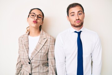 Beautiful couple wearing business clothes looking at the camera blowing a kiss on air being lovely and sexy. love expression.