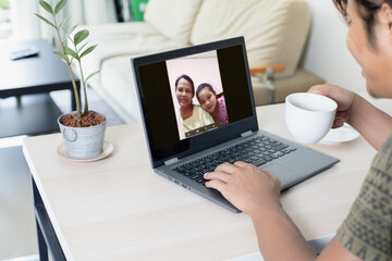 Asia man happy face is having a happy family meeting on a laptop in her home for social distancing concept.