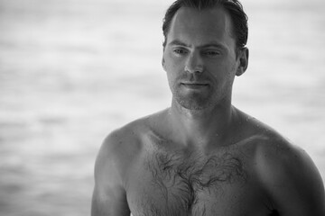Portrait of handsome happy, sexy man with body, surfer  and blue ocean