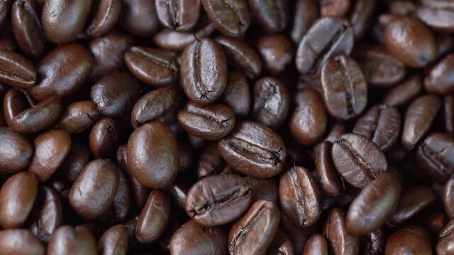 Dark Coffee Grains. Rotating and falling. Coffee beans. Close up of seeds of coffee. Beautiful seeds of coffee.