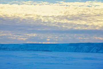 Naklejka na ściany i meble Snowy winter nature in the dusk . Frozen lake landscape with cloudy sky