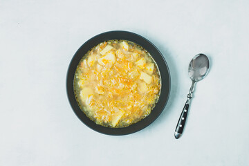 Chicken soup on black bowl on dark black stone table.