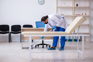 Obraz premium Young male contractor disinfecting clinic in pandemic concept