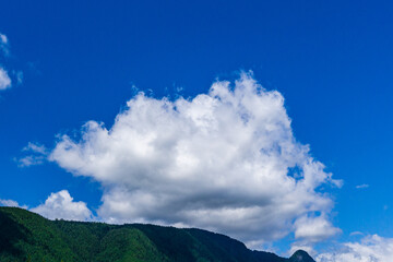 mountains covered with green forest blue sky with white clouds