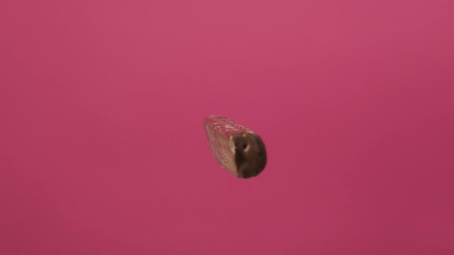 Tasty chocolate candy bar spin on pink background isolate. Unhealthy food for children and all people.