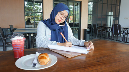 asian business girl is taking notes and is on the phone