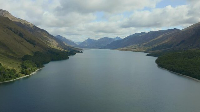 AERIAL: High over North Mavora Lake with forests and mountains around it and snow-capped mountains in the distance. Mavora was used as a location in Lord of the Rings, LOTR. New Zealand, South Island.