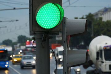  Green traffic light on the background of the road with moving cars.
