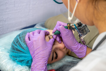 Beautiful woman making permanent makeup in cosmetology salon.