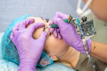 Beautiful woman making permanent makeup in cosmetology salon.