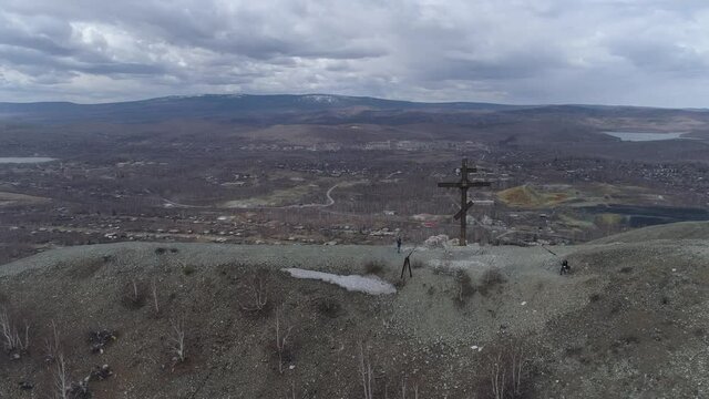 Orthodox cross on Mount Karabash and city view. The camera rises. Russia, Chelyabinsk region