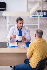 Obraz premium Old neck injured man visiting young male doctor