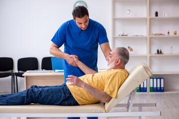 Fototapeta premium Old injured man visiting young male doctor chiropractor