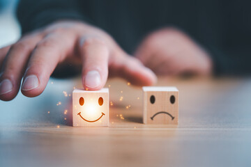 Customer Service rating and satisfaction concept. Hand of client select a feedback with smile face wood cube.