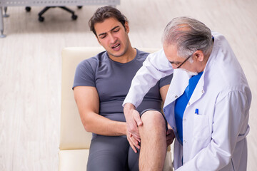 Fototapeta premium Young male patient visiting old doctor traumatologist