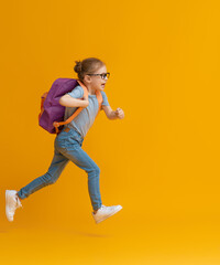 Kid with backpack on color background.
