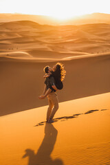 Young happy couple in Sahara desert dunes, Morocco. Happiness, freedom and escape concept. Amazing warm sunset, natural emotions.