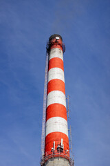 Red and white brick industrial pipe against the blue sky.3