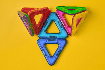 Top view of colorful magnetic building blocks on yellow background