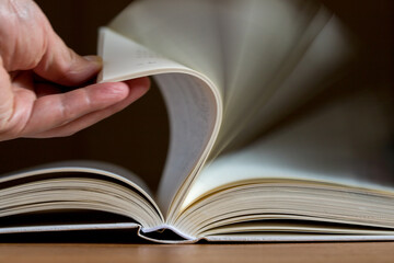 本を開いた大人の片手と本のページ