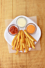 Tasty french fries on wooden table background