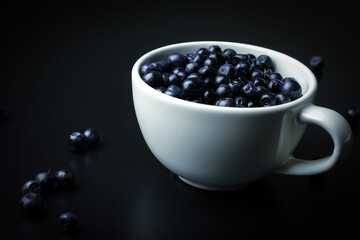 Blueberry in white cup on the black background