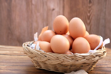 Chicken eggs in basket on wood table background and space for text