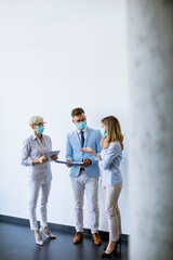 Business partners standing and looking at business results in office  while wearing face masks sa an virus protection