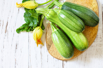 Fresh healthy uncooked green zucchini on a wooden kitchen table. Diet menu concept. Top view flat lay background. Copy space.