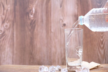 Pouring drinking water in glasses on wood table background and space for text