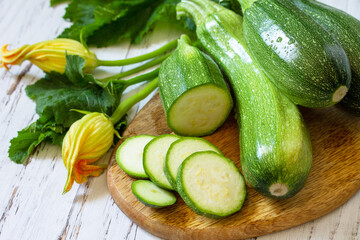 Fresh healthy uncooked green zucchini on a wooden kitchen table. Diet menu concept.