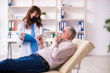 Fototapeta premium Old man visiting young female doctor for plastic surgery