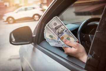 businessman pays for a product or service, gives dollars while sitting in the car.