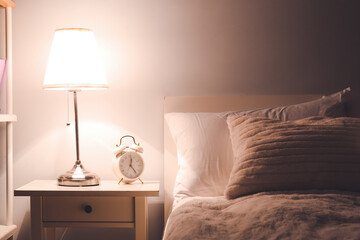 Glowing lamp on bedside table in evening