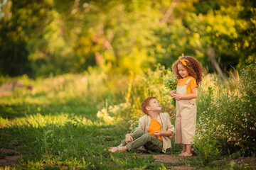 Cheerful happy Children brother and sister on a walk in the forest with a bouquet of daisies.