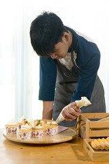 Motion blur Asian teenager boy decorating cupcakes at home, lifestyle concept.