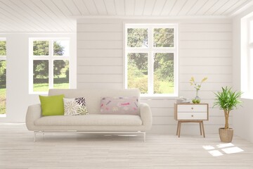 Fototapeta premium White living room with sofa and summer landscape in window. Scandinavian interior design. 3D illustration