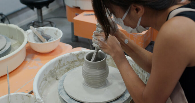 Woman make pottery wheel, shaping a clay pot