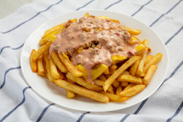 Homemade Animal Style French Fries on a white plate, side view. Close-up.