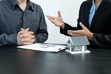 A real estate agent with a home model is talking to clients about renting a house and buying home insurance and contracting the contract after the formal negotiation is completed