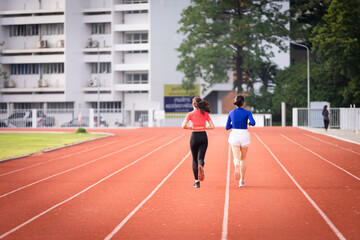 Fototapeta premium Young fitness woman runner jogging excercise in the morning on city stadium track in the city. Female athlete excercise in the city stadium to keep body fitness. Stock photo.